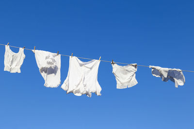 Low angle view of laundry drying on clothesline against blue sky