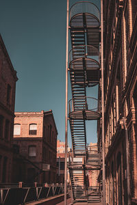 Low angle view of historical building fire escape staircase against blue sky