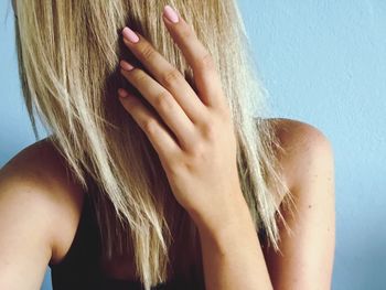 Close-up of woman with blond hair against wall