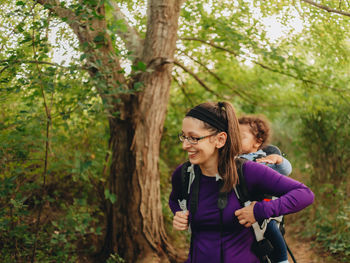 Smiling mother with cute son on back standing on forest