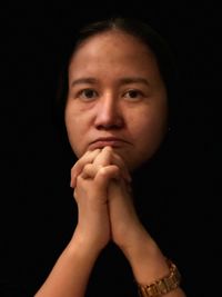 Close-up portrait of beautiful young woman over black background