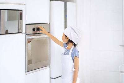 Woman holding umbrella while standing in kitchen