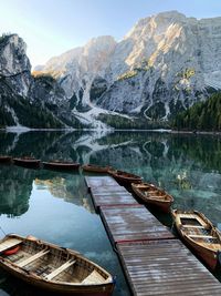 Boats moored by pier in lake against mountains