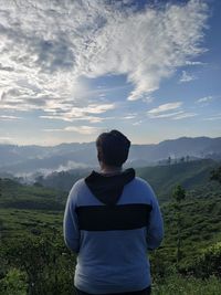 Rear view of man looking at mountains against sky