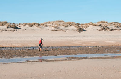 Man walking on beach against sky