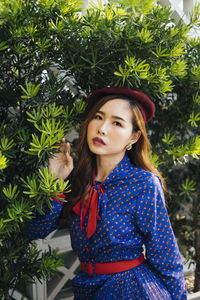 Portrait of smiling young woman standing against plants