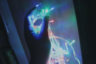 Close-up of hand holding illuminated string light 