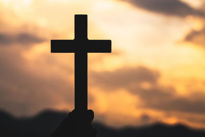 Silhouette cross against sky during sunset