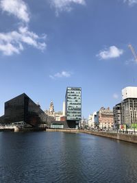 Bridge over river by buildings in city against sky