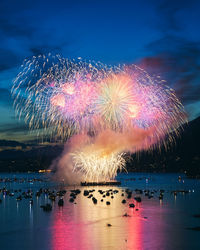 Firework display over lake against sky at night
