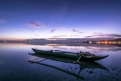 Boats moored on sea against sky at sunset