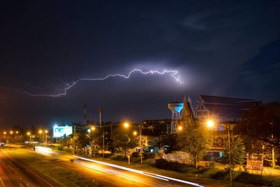 High angle view of light trails on street against lightning in cloudy sky