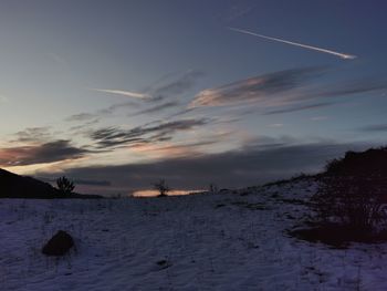 Scenic view of snow covered field against sky at sunset