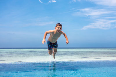 Funny kid jumping into a infinity swimming pool