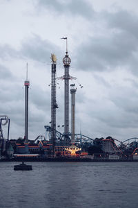 Cranes in front of sea against sky