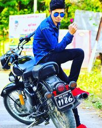 Young man wearing sunglasses sitting on bicycle