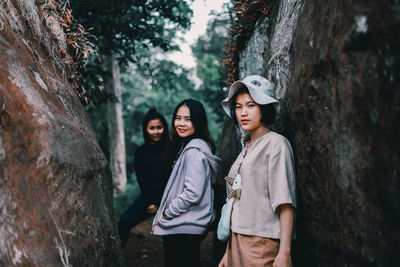 Young woman standing by tree trunk