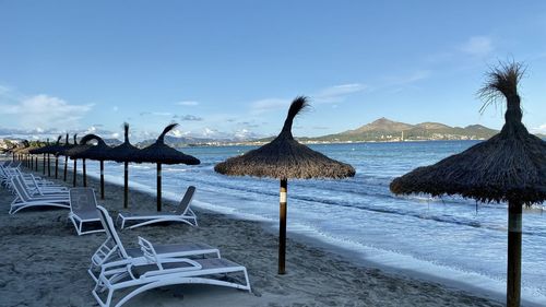 Chairs and parasols on beach against sky