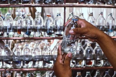 Midsection of man holding glass bottles