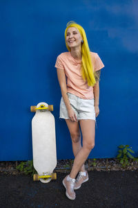 Portrait of a smiling young woman against blue wall