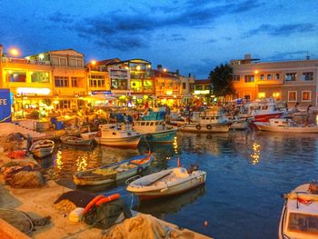Boats moored at harbor against buildings at dusk