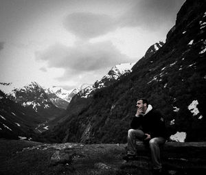 Man sitting on rock against mountains