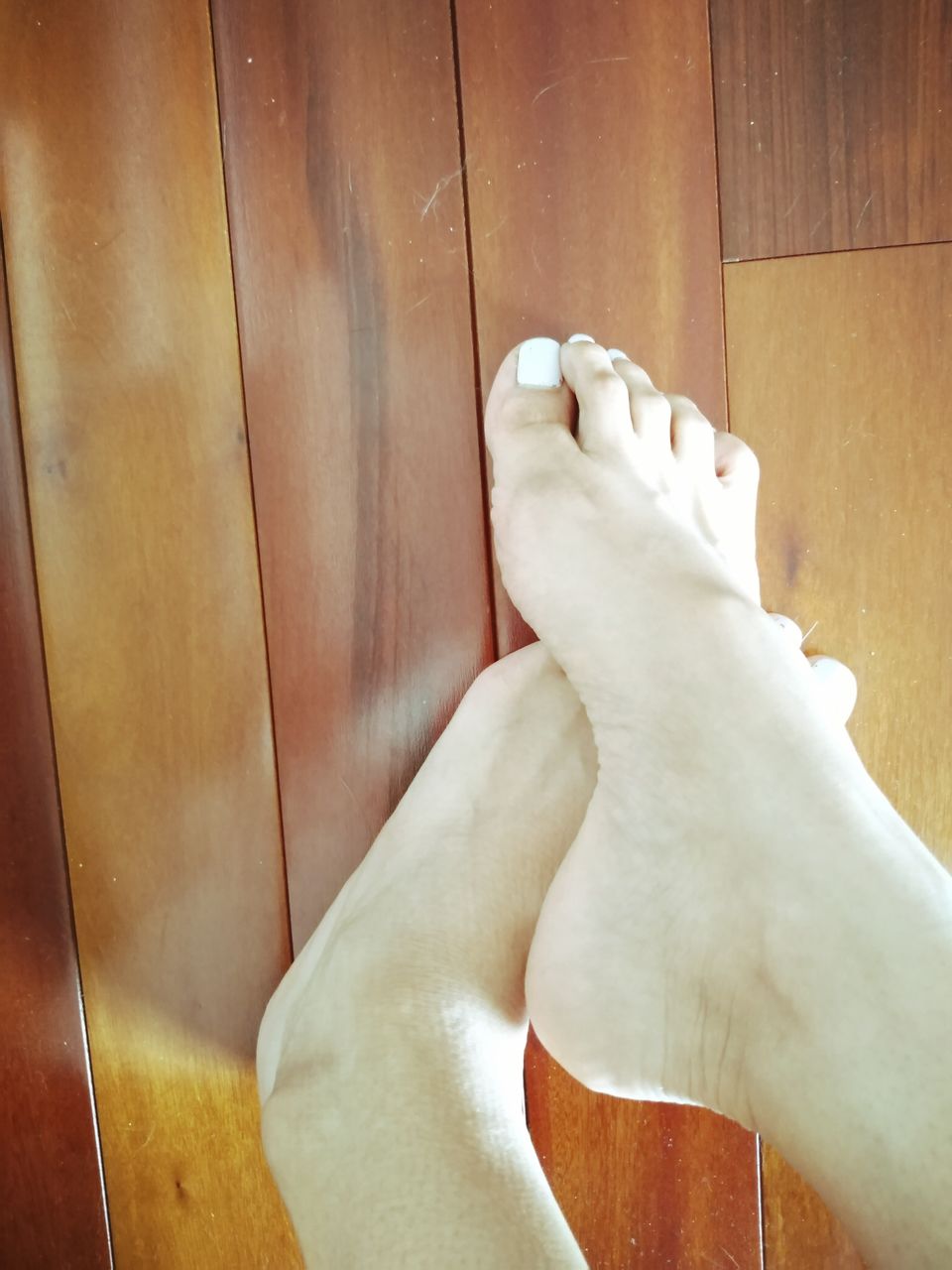 human leg, low section, human foot, limb, indoors, one person, human limb, wood, personal perspective, barefoot, adult, lifestyles, flooring, shoe, hand, toe, footwear, relaxation, leisure activity, women, high angle view, hardwood floor