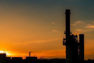 Low angle view of silhouette factory against sky during sunset