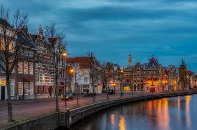 River by buildings against blue sky at dusk