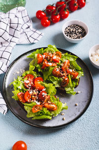 Sandwich with tomatoes and lettuce on rye bread on a plate on the table vertical view