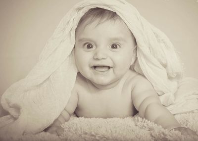 Portrait of cute baby girl lying on bed