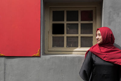 Young woman standing against window