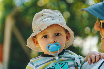 Close-up of baby boy with pacifier in mouth being carried by father