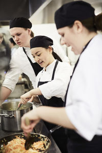 Male and female chefs cooking food in kitchen at restaurant