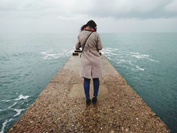 Rear view full length of woman amidst sea on groyne