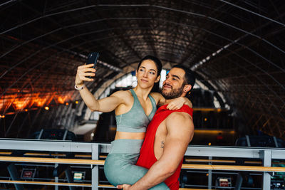 Portrait of young couple in love standing in gym happy wearing gym clothes