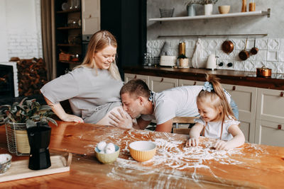 A happy family with a child cook and have fun with flour in a cozy kitchen at home