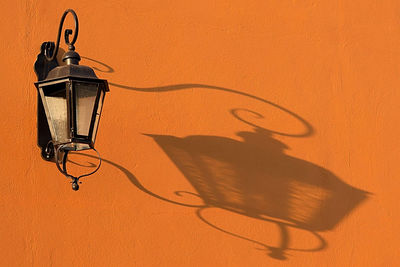 Close-up of electric lamp against orange wall