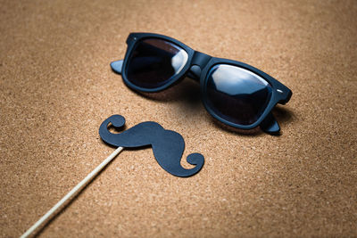 High angle view of mustache prop and sunglasses on table