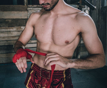 Midsection of shirtless man standing outdoors