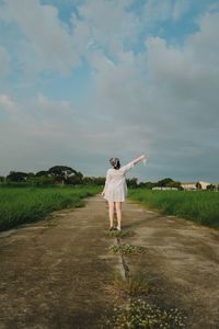 Rear view of woman walking on field against sky