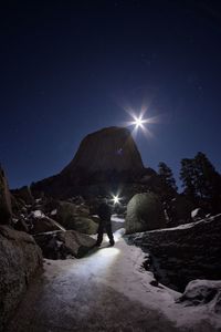 Rear view of person standing on mountain against sky at night