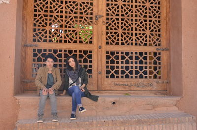 Friends sitting on steps against door of building