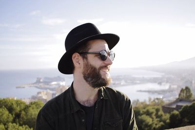 Close-up of man looking away from camera with bay in the background