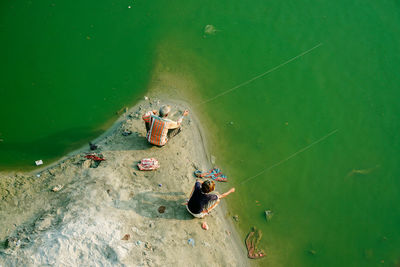 High angle view of boy and man fishing in green river