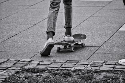 Low section of man skateboarding on footpath