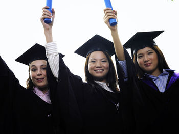 Portrait of smiling students wearing graduation gowns