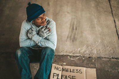 Full length of man sitting against wall