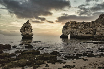 Rocks on sea shore against sky during sunset