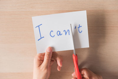 Cropped hand of person holding paper on table